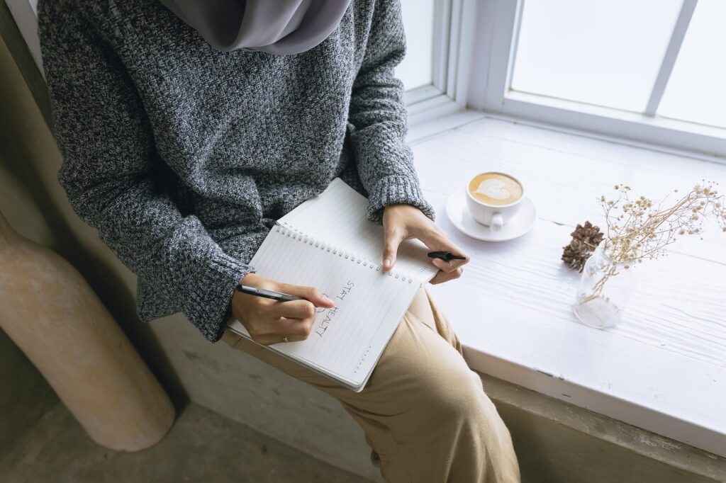 Image of a person journaling with a cup of coffee.